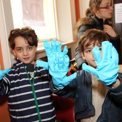 Photograph of two children wearing gloves and holding their hands up to the camera