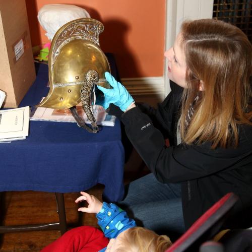 Woman and young child looking at a brass fireman's helmet