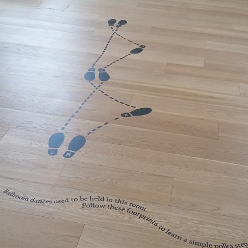 Footsteps marking the positions for a dance in black on the pale Assembly Room floor