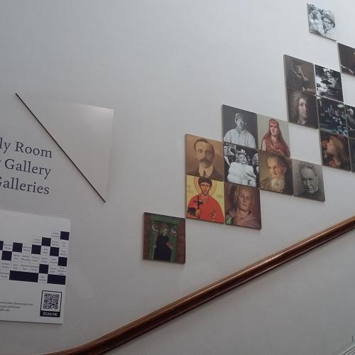 Display of portraits of people on the wall of the Grand Staircase with an information panel at the bottom