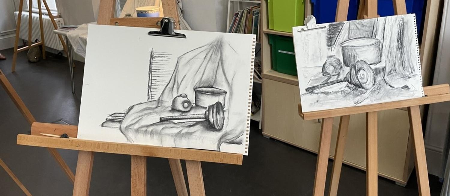 Colour photograph showing two easels with charcoal sketches in progress