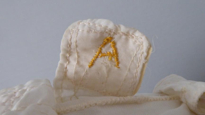 Photo of detail from John Allam's white inner helmet liner with embroidered yellow "A"