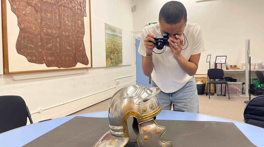 A woman photographs a replica Roman helmet