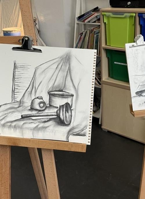 Colour photograph showing two easels with charcoal sketches in progress