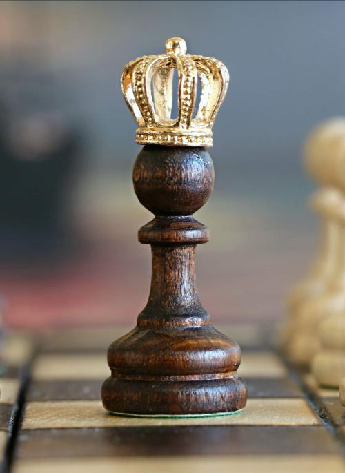 chess piece poawn with a gold crown on top